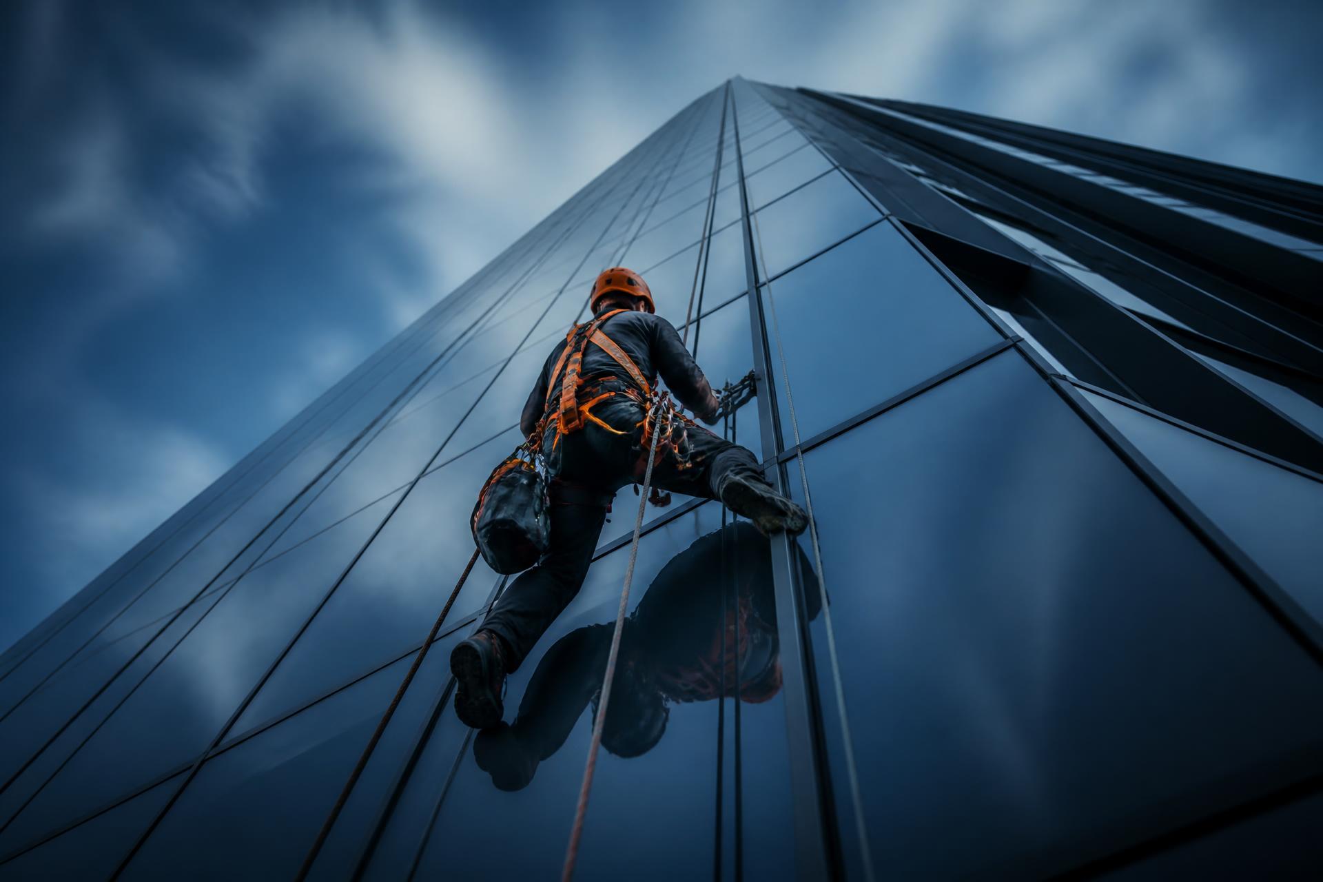 Técnico de trabajos verticales trabajando en la fachada acristalada de un rascacielos